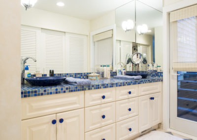 Abbey's custom bathroom design, white cabinets with blue accents. Dual elevated bowl sinks