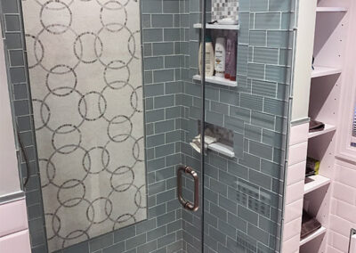 Abbey's designed bathroom, glass tile shower with tile mosaic, storage nook