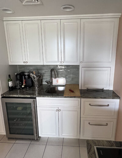 View of kitchen end wall, wine fridge, sink, appliance garage